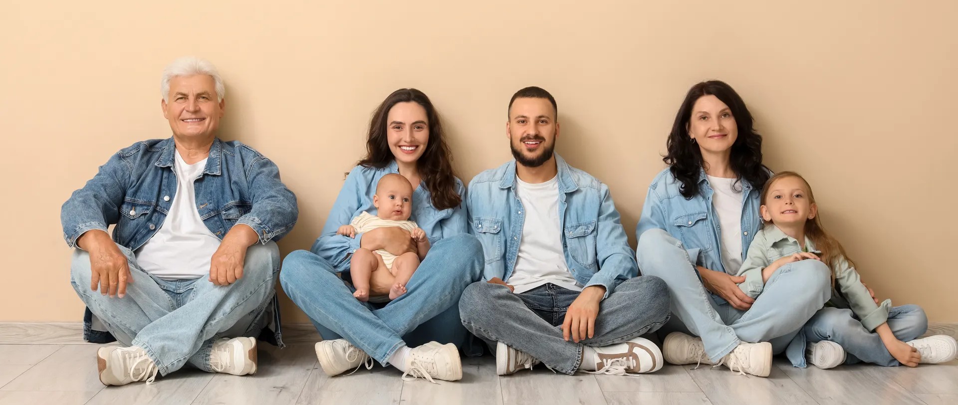 Familie vier Erwachsene und ein Kind welche auf dem Boden sitzen